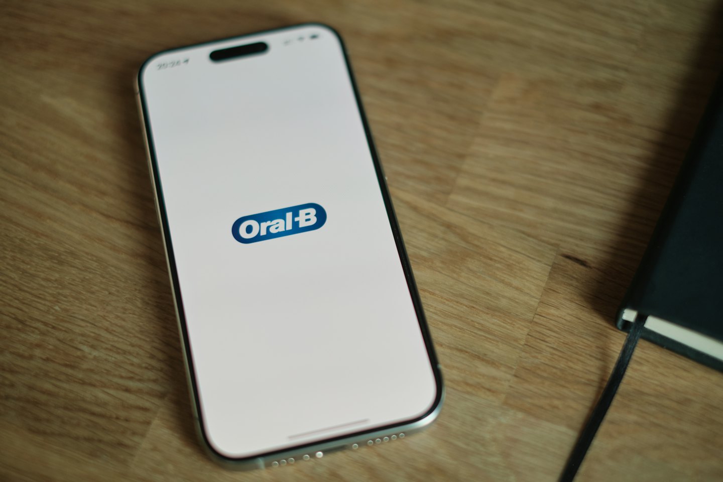 Smartphone mit Oral-B Logo auf einem Holztisch.